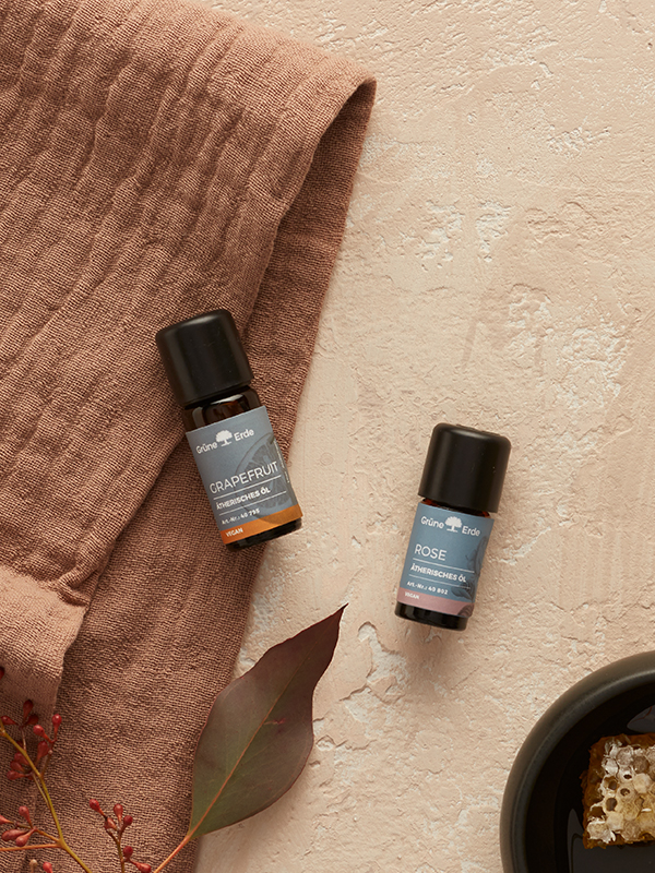 Ätherische Öle auf Stoff mit Honig und Blättern stilvoll arrangiert