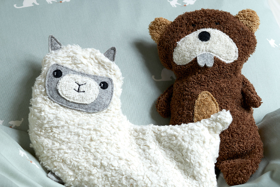 Kuscheltiere in Biber und Lama Form Form auf einer Decke sitzend