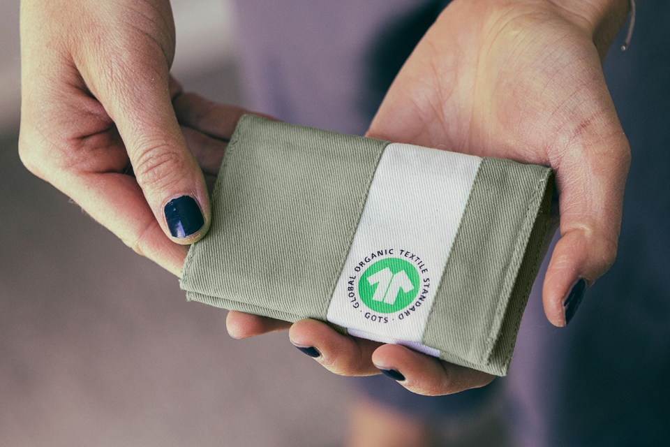 Hände halten ein Stoffmuster mit einem Logo darauf