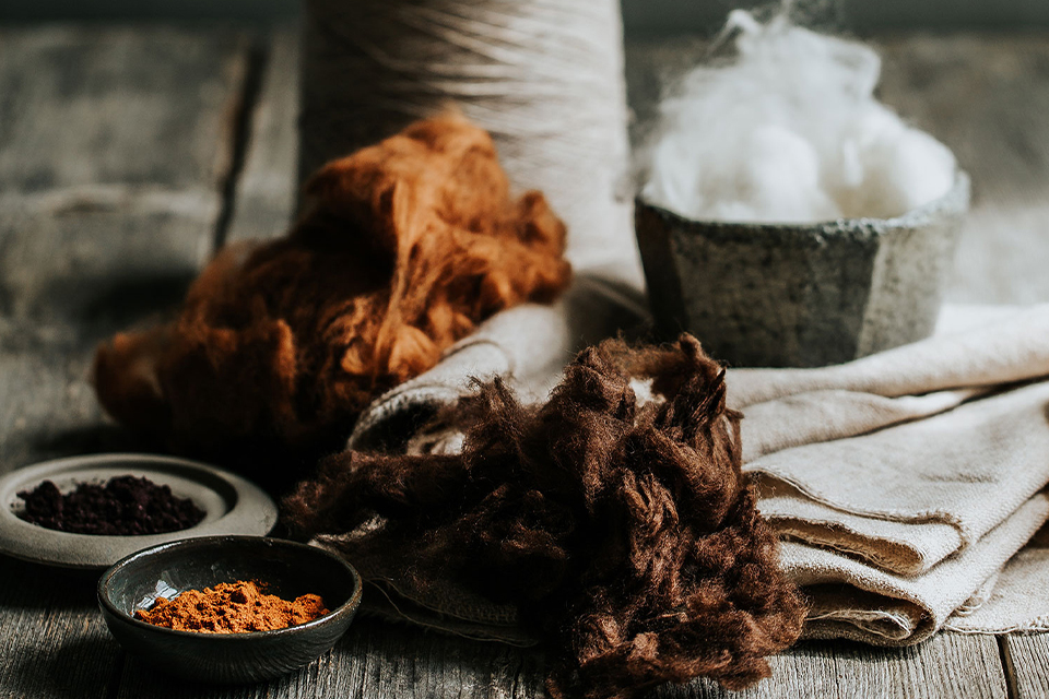 Naturtextilien mit Fasern und Schalen in rustikaler Umgebung