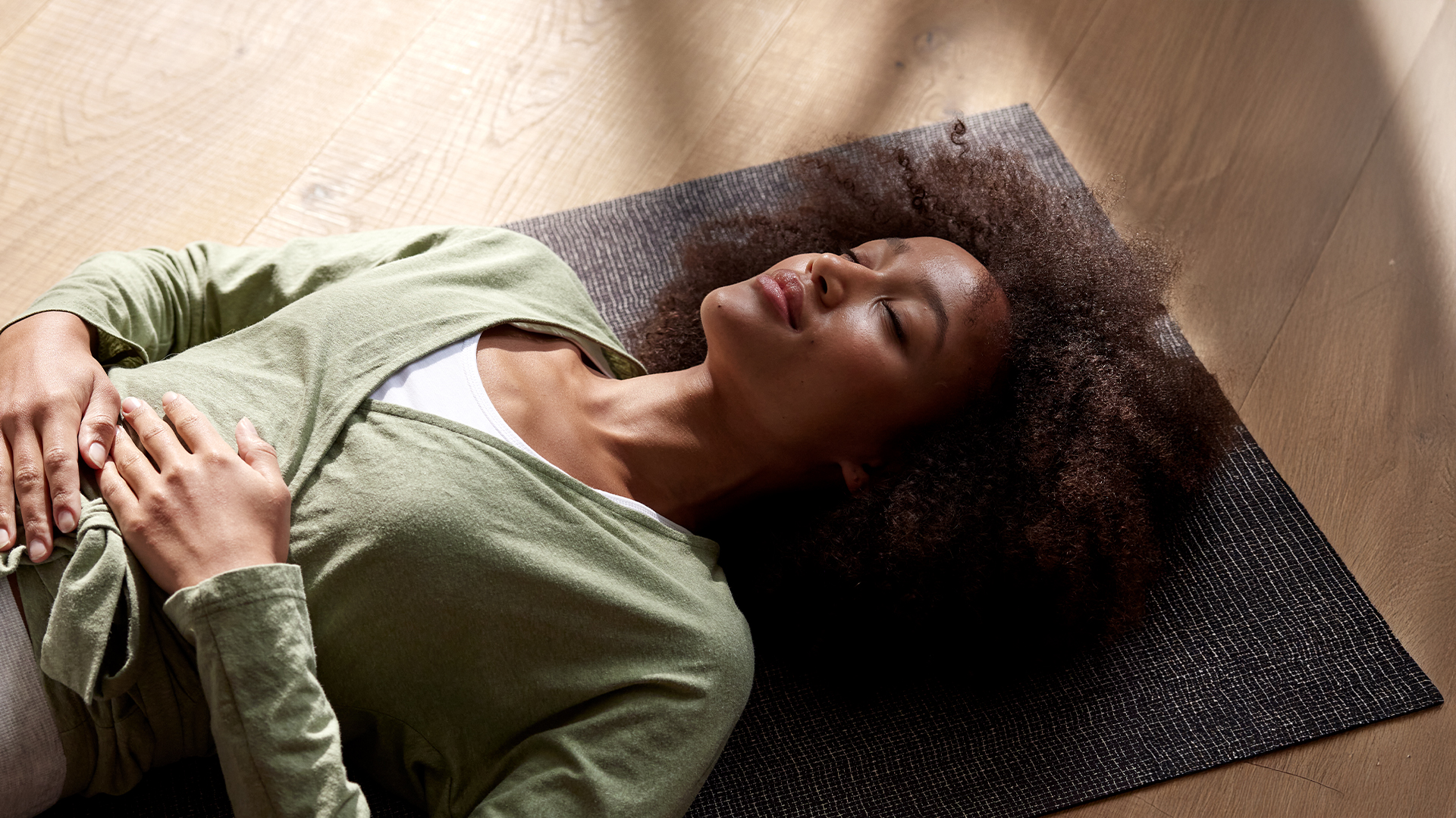 Frau liegt entspannt auf Yogamatte mit geschlossenen Augen