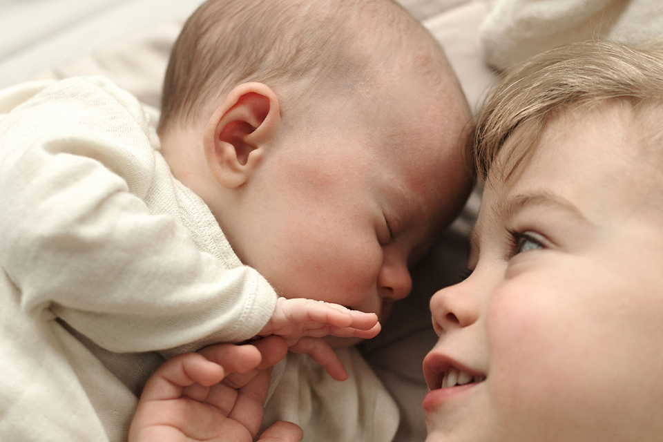 Ein Baby schläft Kopf an Kopf mit seinem Geschwisterchen