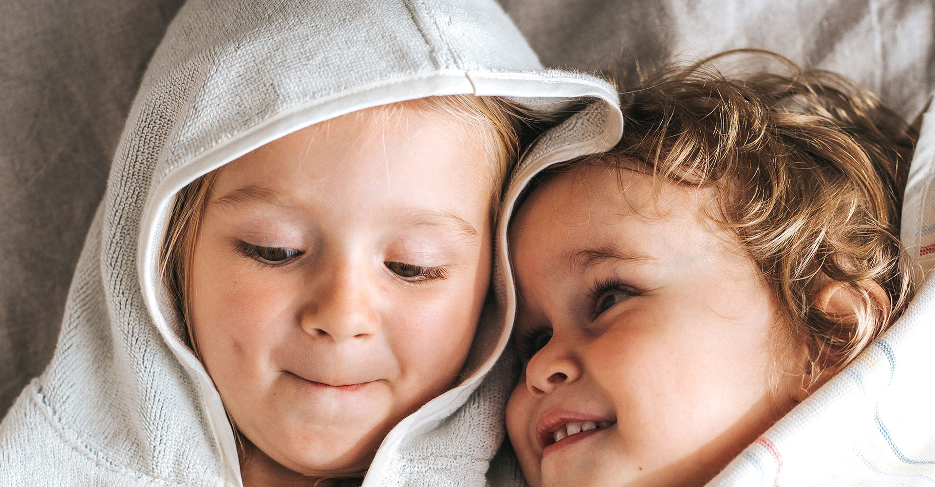 Zwei Kleinkinder in Bade-Ponchos gehüllt
