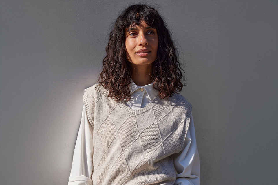 Frau trägt hellen Pullover vor neutralem Hintergrund