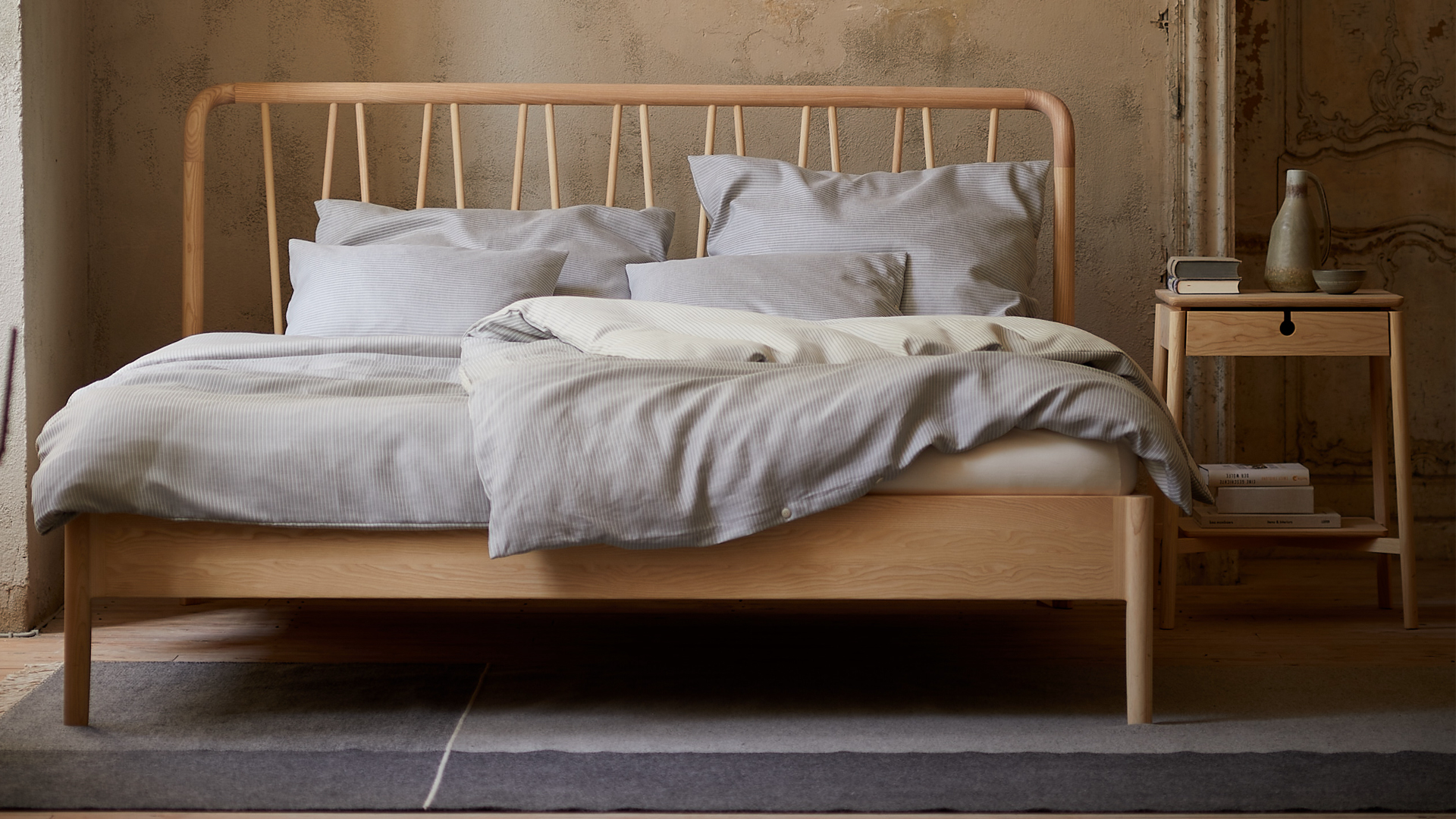 Massivholz Doppelbett Abea mit Holzbetthaupt und Nachtkästchen im Schlafzimmer mit Bettdecken und Pölster