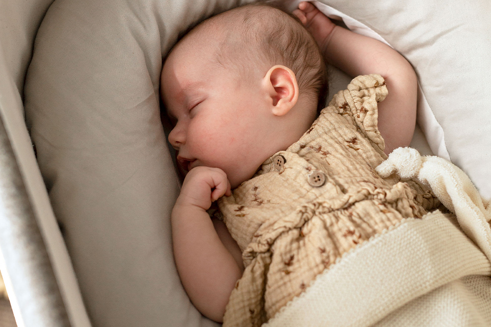 Baby mit Kuschelschlange schlafend in einer Babywiege liegend
