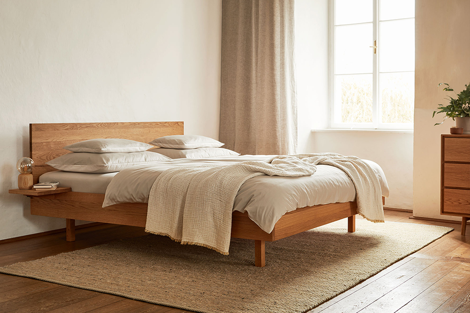 Holzbett in hell beleuchtetem Schalfzimmer