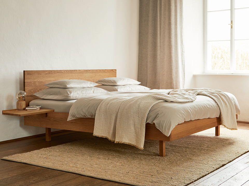 Holzbett in hell beleuchtetem Schalfzimmer