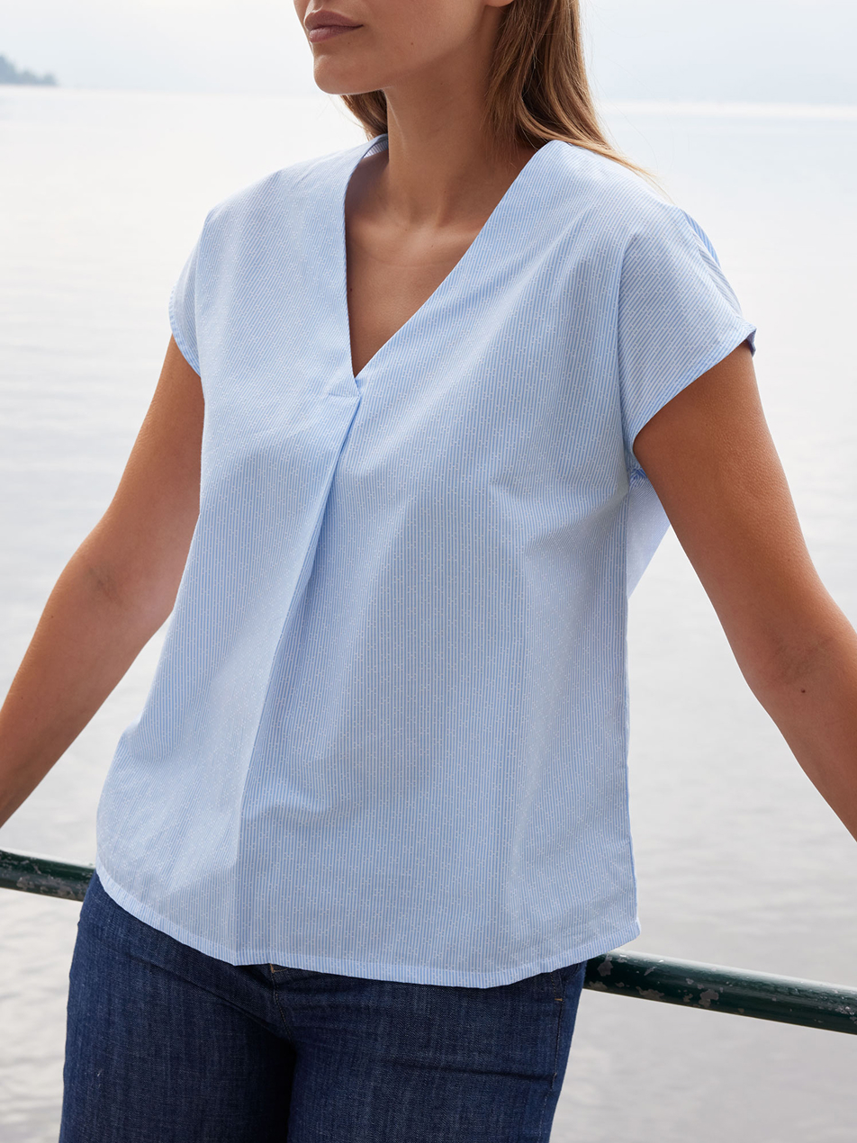 Frau in blauer kurzärmeliger Bluse und dunkelblauer Jeans