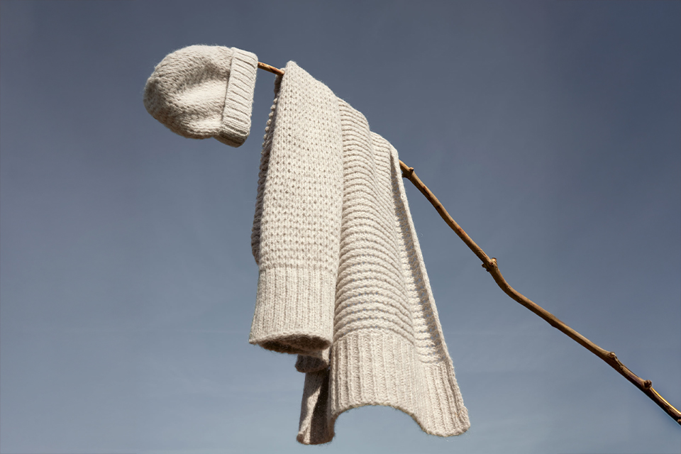 Beiger Mantel hängt dekorativ an einem Ast im Wind