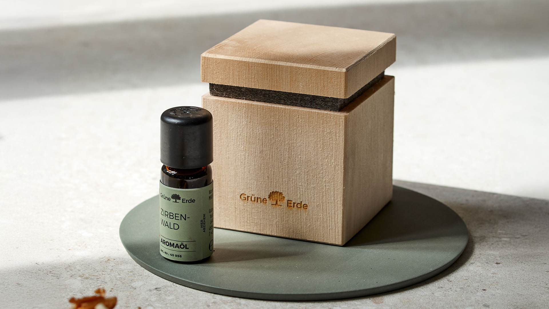 Holzbox und Aromaöl auf runder Platte im Sonnenlicht