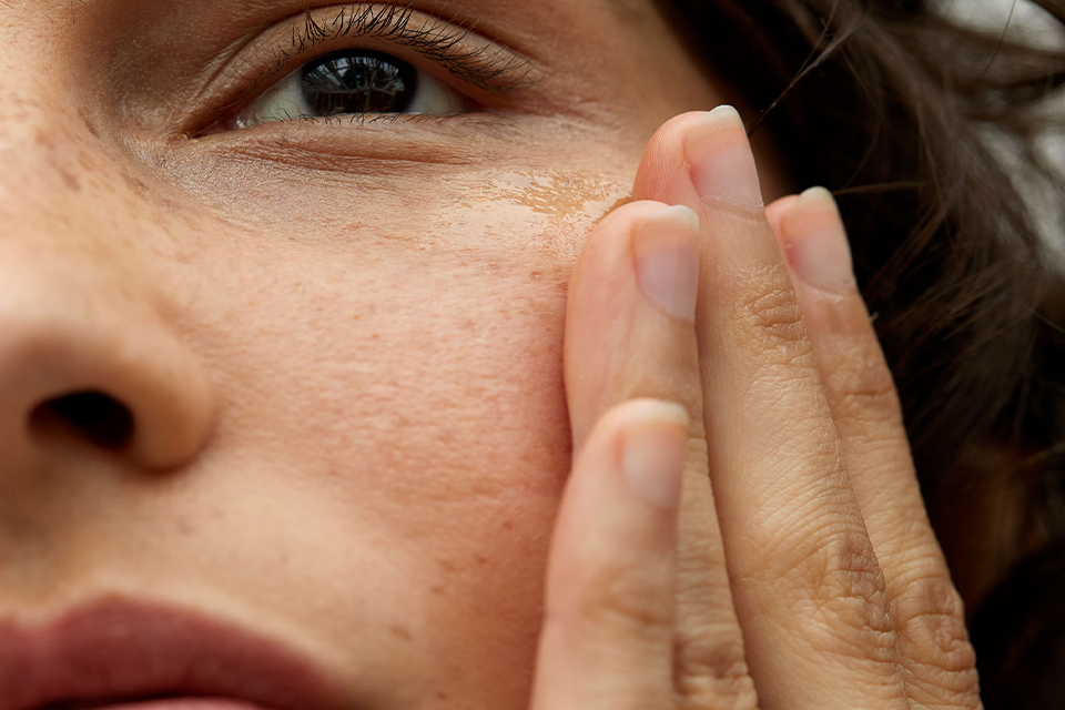 Linke Hälfte eines Frauengesichtes mit einer Hand an der Wange