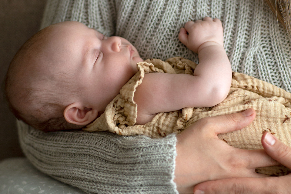 Schlafendes Baby im Arm der Mutter liegend