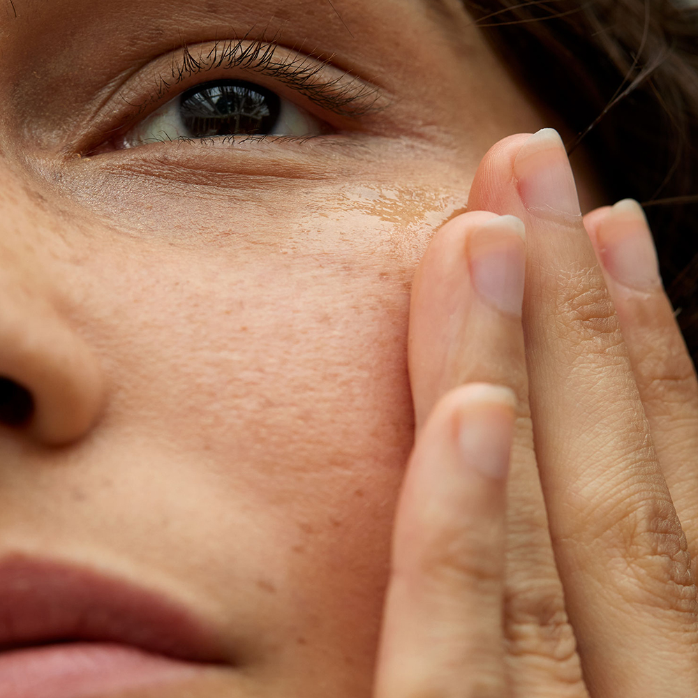 Linke Hälfte eines Frauengesichtes mit einer Hand an der Wange