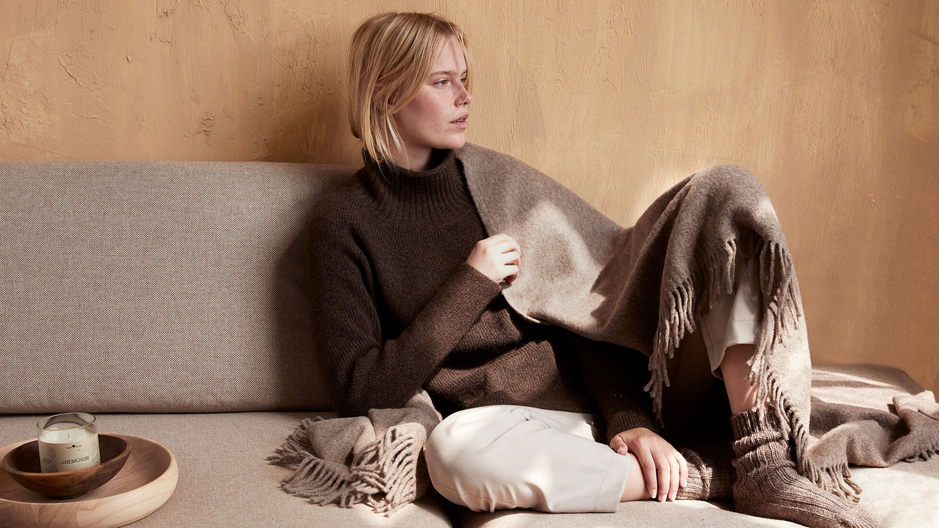 Frau entspannt mit Buch auf Sofa in ruhiger Umgebung