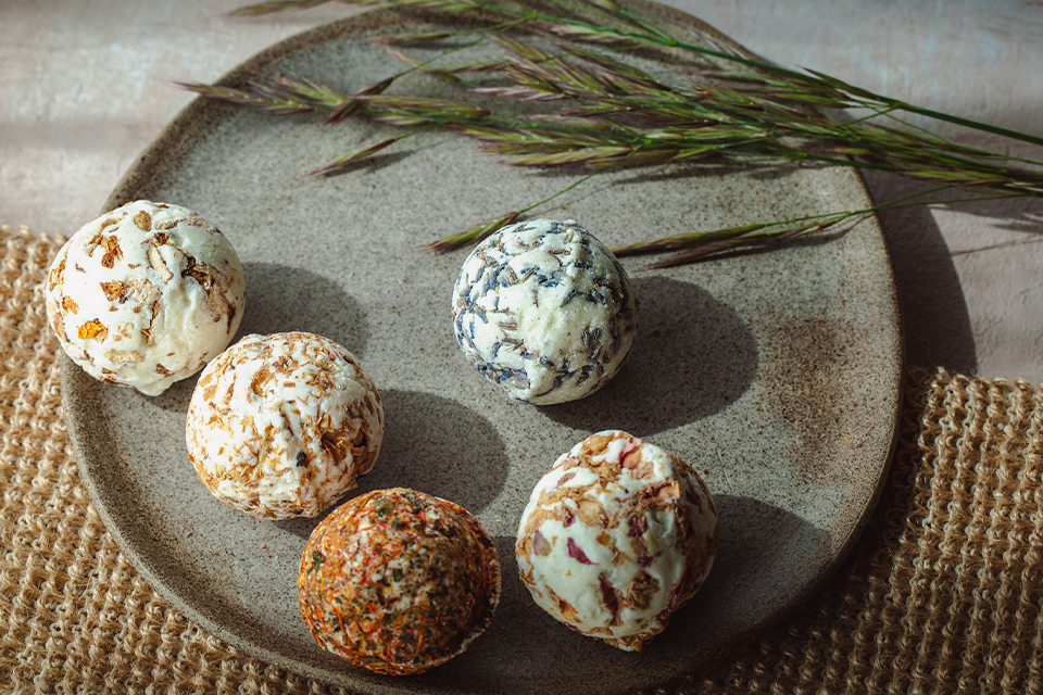Handgemachte Badekugeln auf Teller mit Kräutern dekoriert
