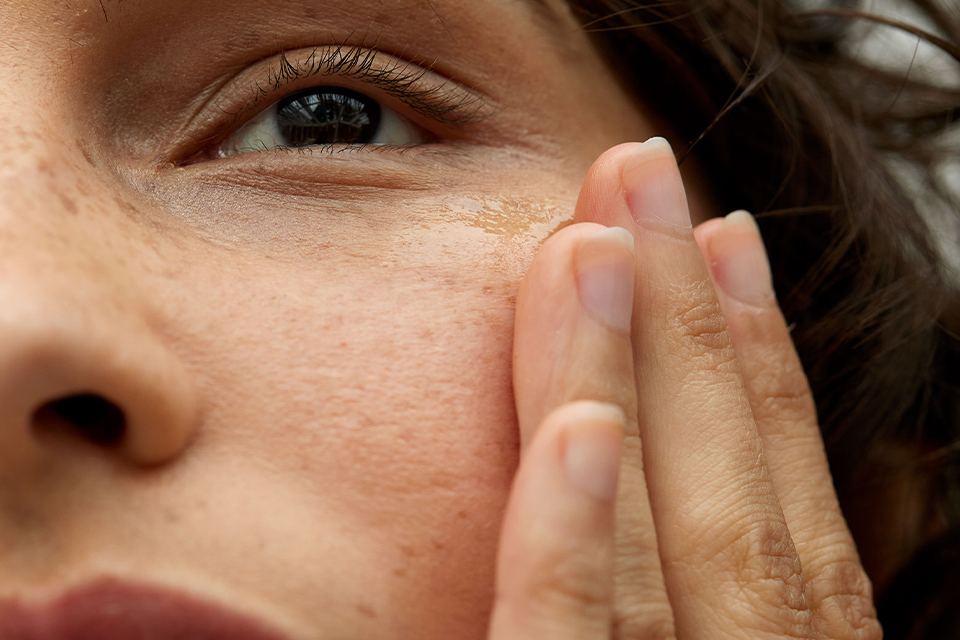 Linke Hälfte eines Frauengesichtes mit einer Hand an der Wange