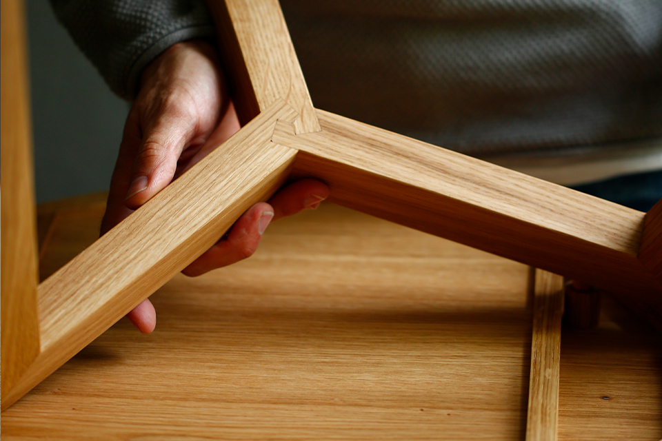 Hand hält Tischbeine aus Holz