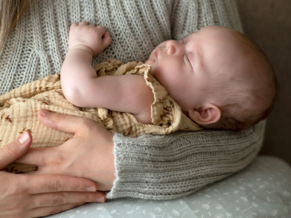 Schlafendes Baby im Arm der Mutter liegend