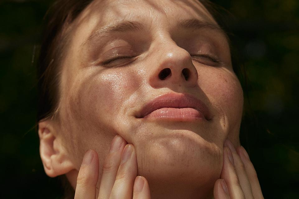 Frau trägt mit geschlossenen Augen blickt in die Sonne