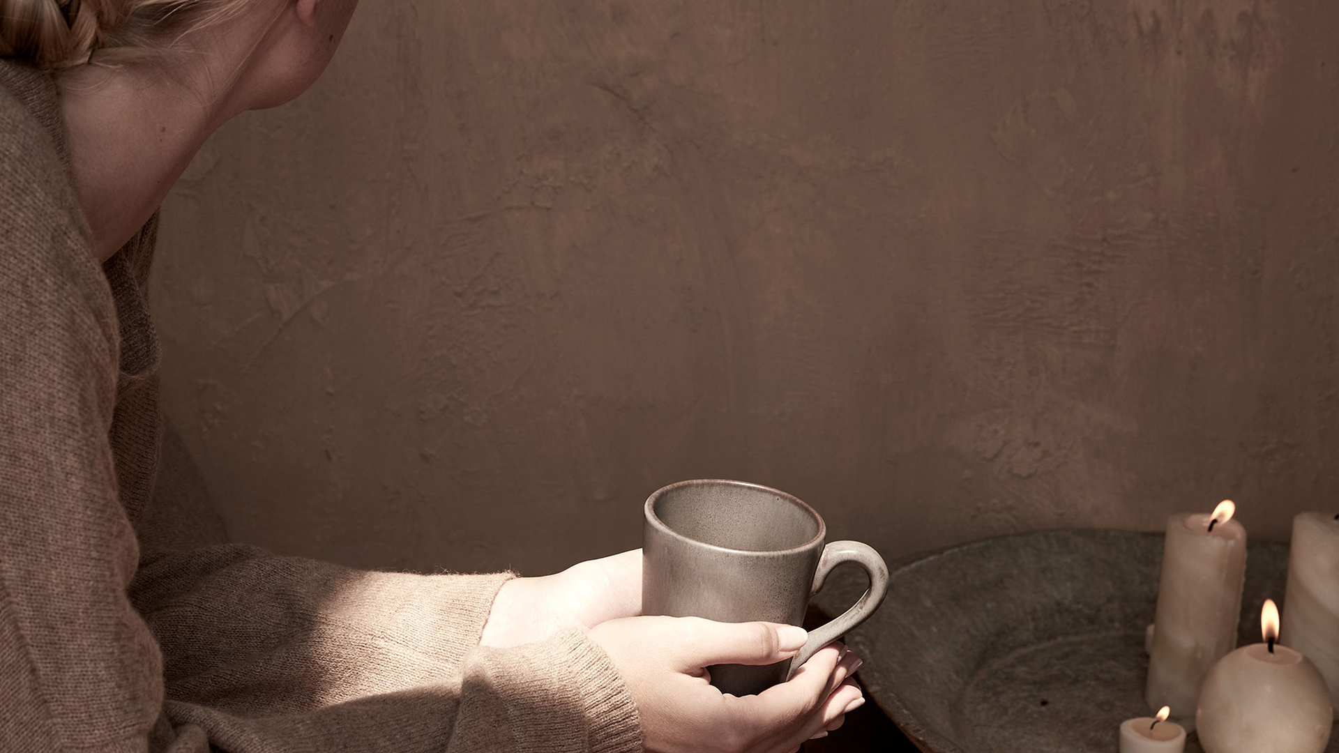 Hände halten warme Tasse in ruhiger minimalistischer Umgebung