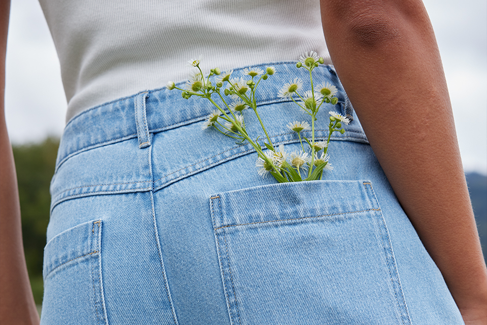 Blumen schauen aus der Tasche einer hellblauen Jeanshose heraus