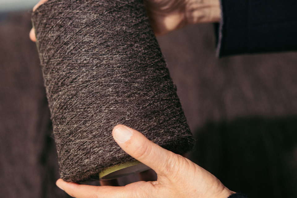 Hand hält dunkelbraune Stoffrolle