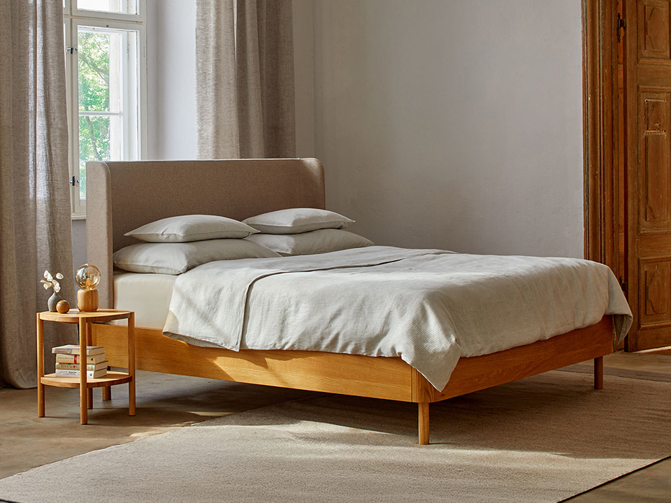 Massivholzbett Tonda mit hohem Polsterbetthaupt im Schlafzimmer