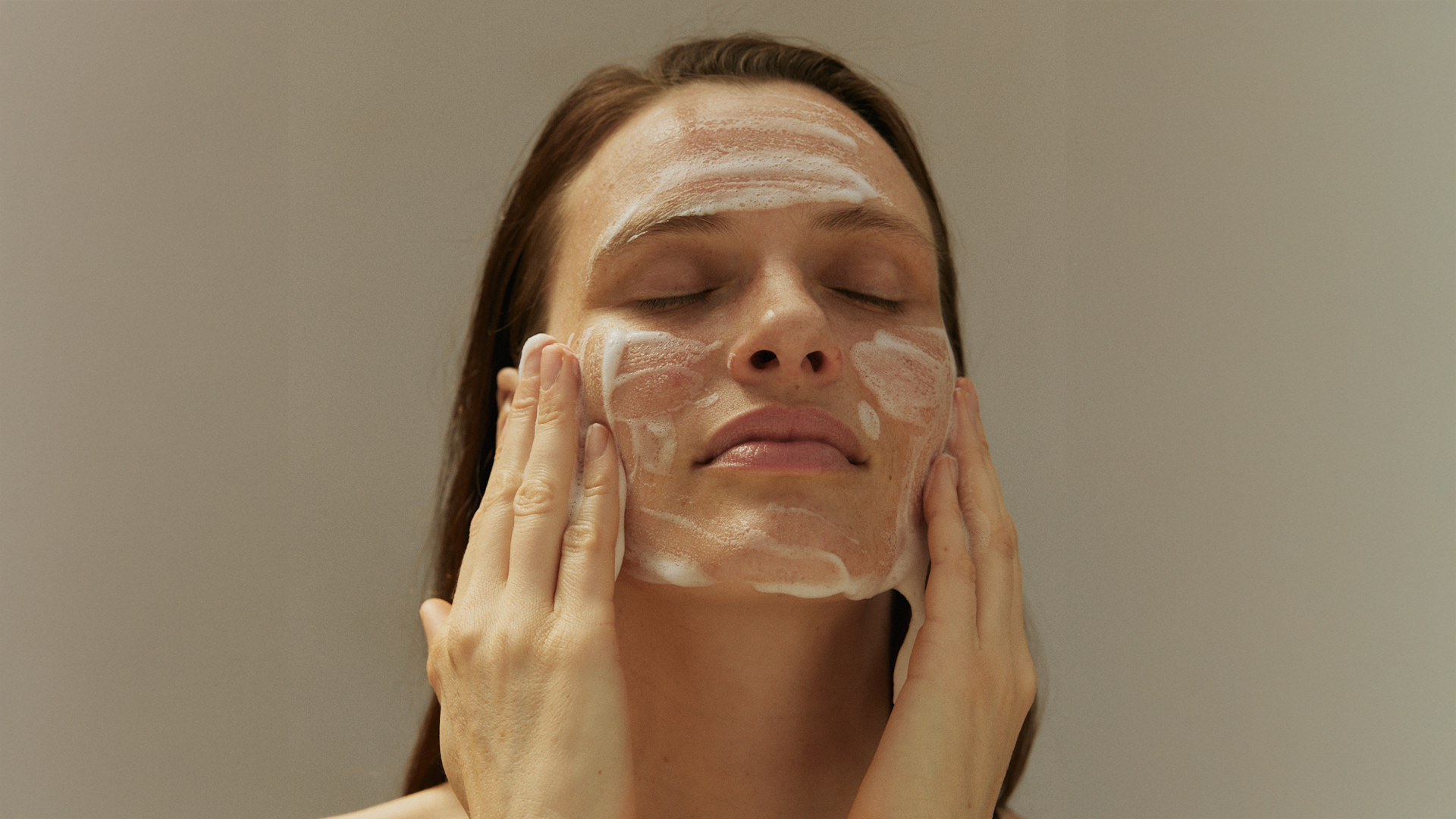 Frau reinigt ihr Gesicht mit einem Reinigungsschaum