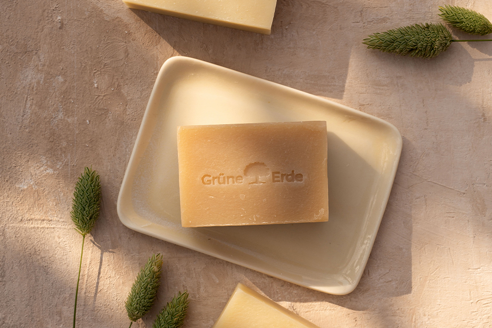 Festes Duschgel in einer Schale neben dekorativen grünen Zweigen