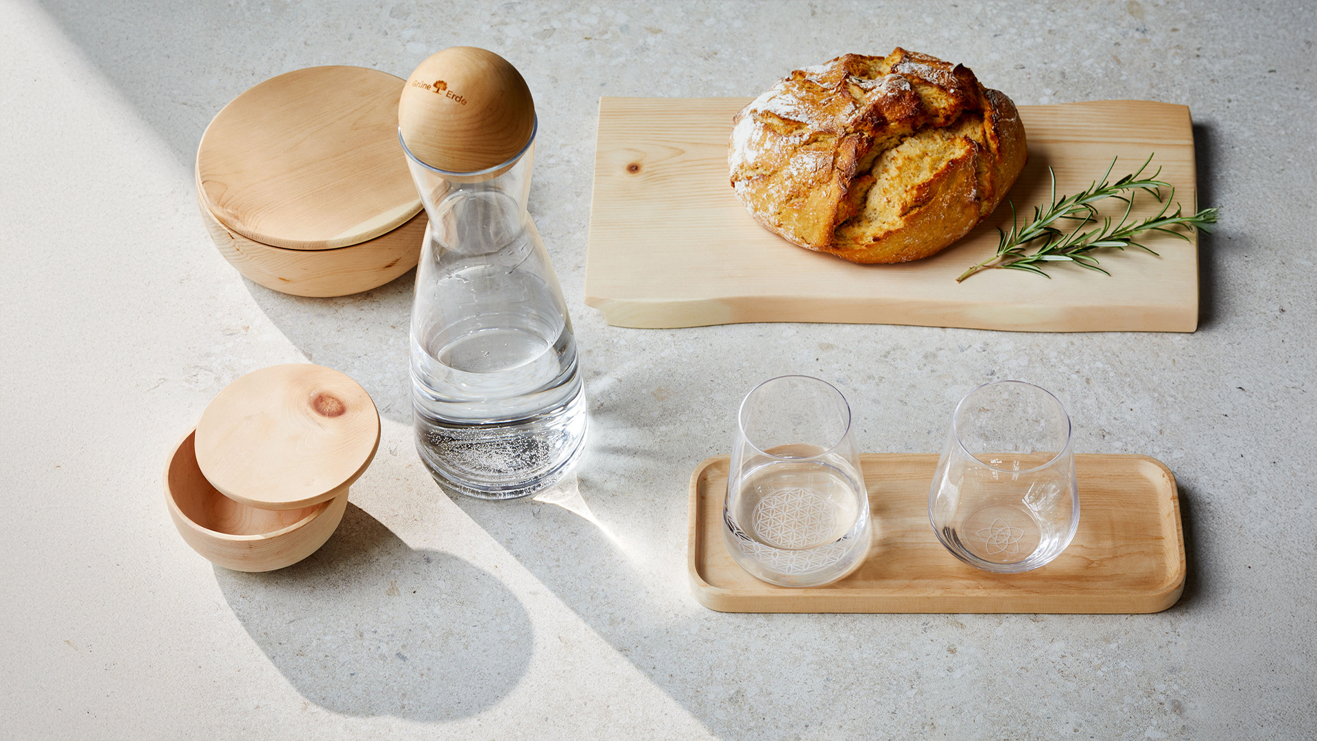 Holzbrett und Holzschüsseln miteiner Glaskaraffe und Gläsern auf einem Tisch stehend