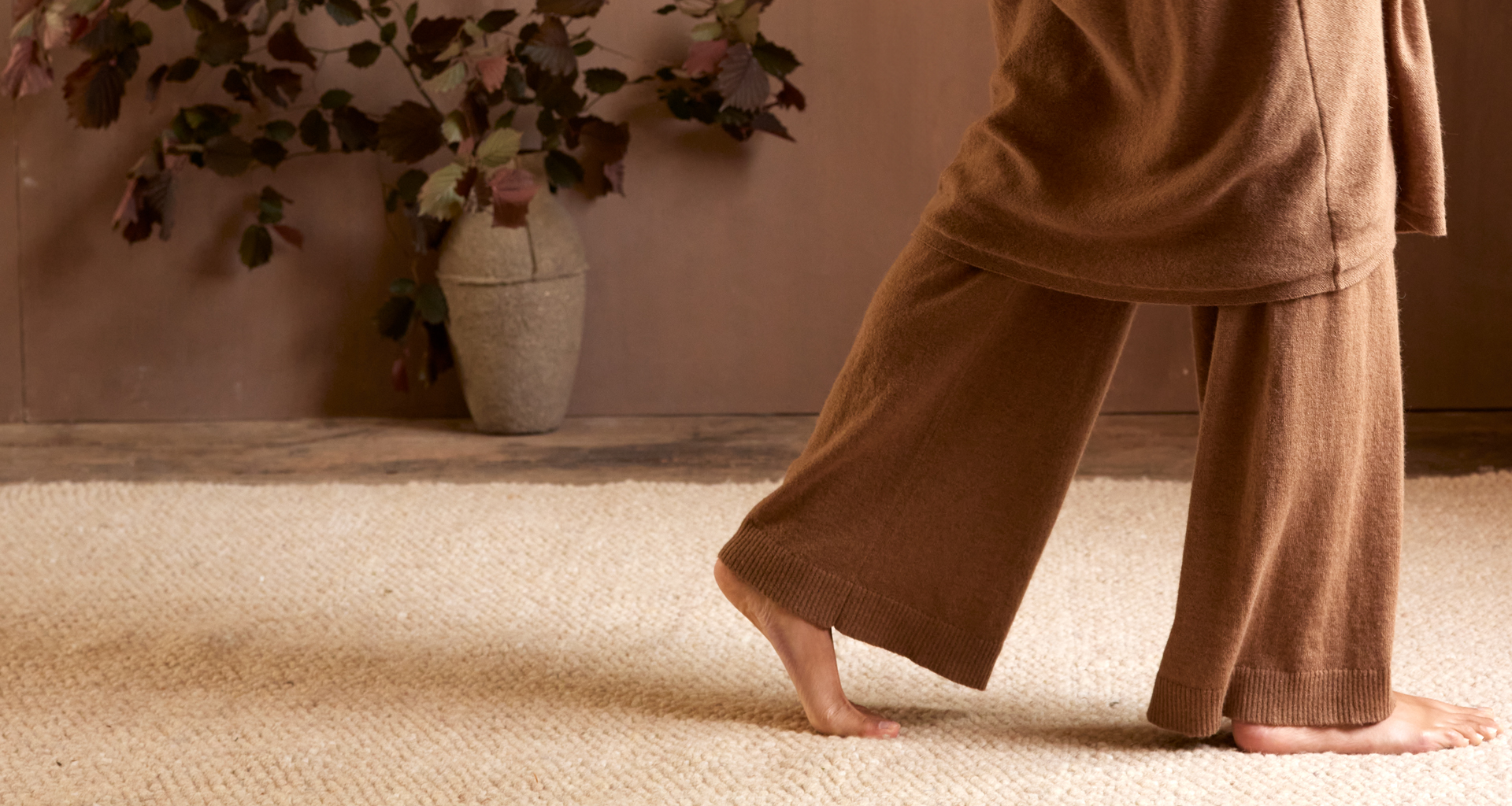 Frau in Yogakleidung geht barfuß über einen Teppich