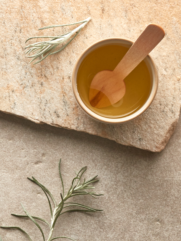 Schale mit Öl und Kräutern neben ätherischen Ölen natürlich arrangiert