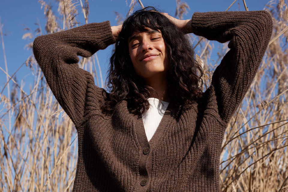 Frau im braunen Pullover genießt Sonne im Freien