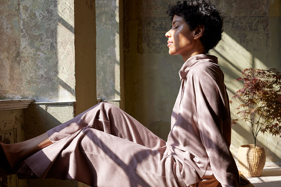 Frau in Loungwear entspannt vor einem Fenster