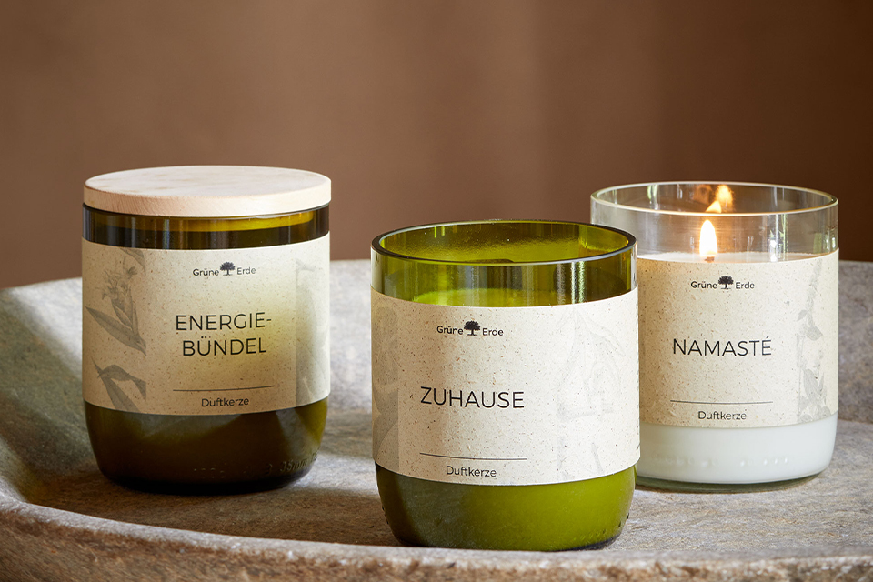 Drei Duftkerzen in einem Dreieck arrangiert auf einer Keramikschüssel