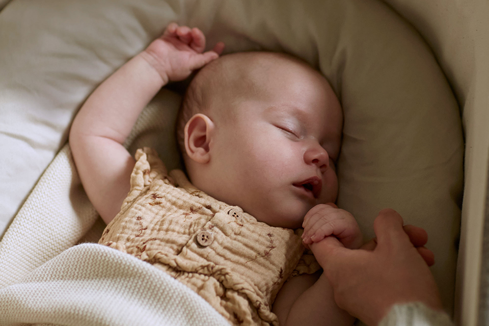 Baby mit Kuschelschlange schlafend in einer Babywiege liegend