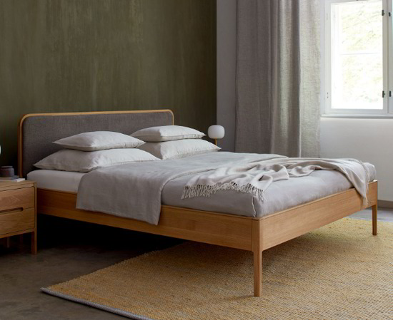 Bett Philomena in grau steht auf einem hellgrauen Teppich im Schlafzimmer