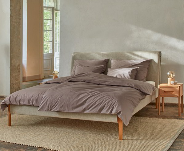 Holzbett steht auf grauem Teppich im Schlafzimmer