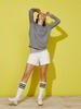 Model vor gelbem Hintergrund mit Shorts und Pullover in Wickeloptik