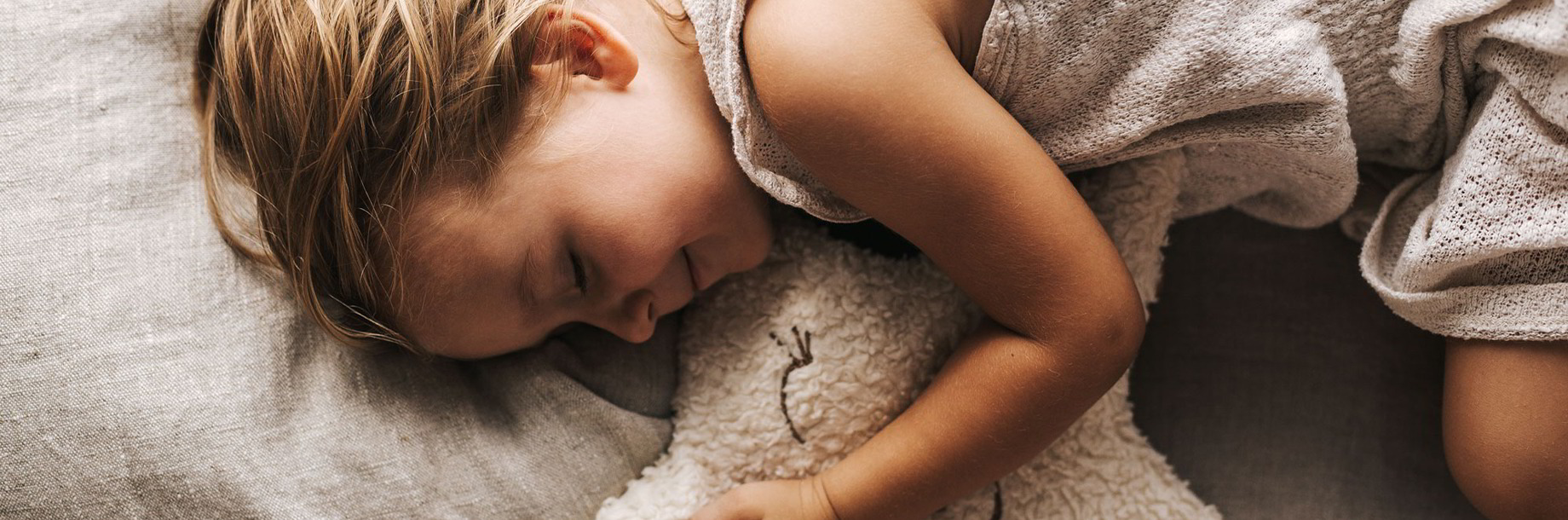 Grüne Erde Kinderschlaftextilien, Kinder schlafen gemütlich in Naturbettwäsche, Nestchen und Kuscheltier in Gitterbett