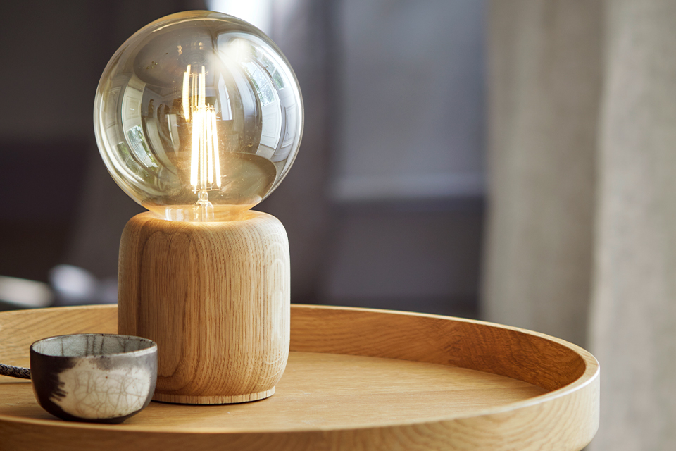 Tischlampe mit Glühbirne auf Holztablett