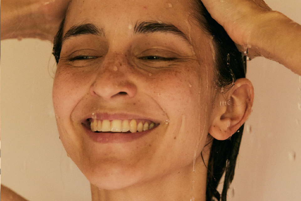 Frau wäscht sich lächelnd die Haare