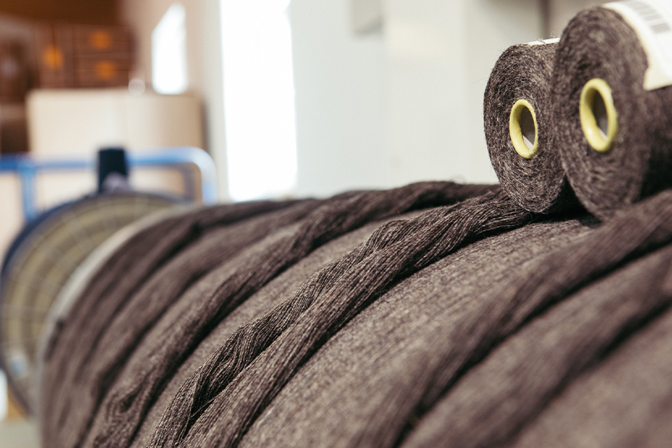 Dunkelbraune Stoffrollen liegen auf großer Stoffrolle