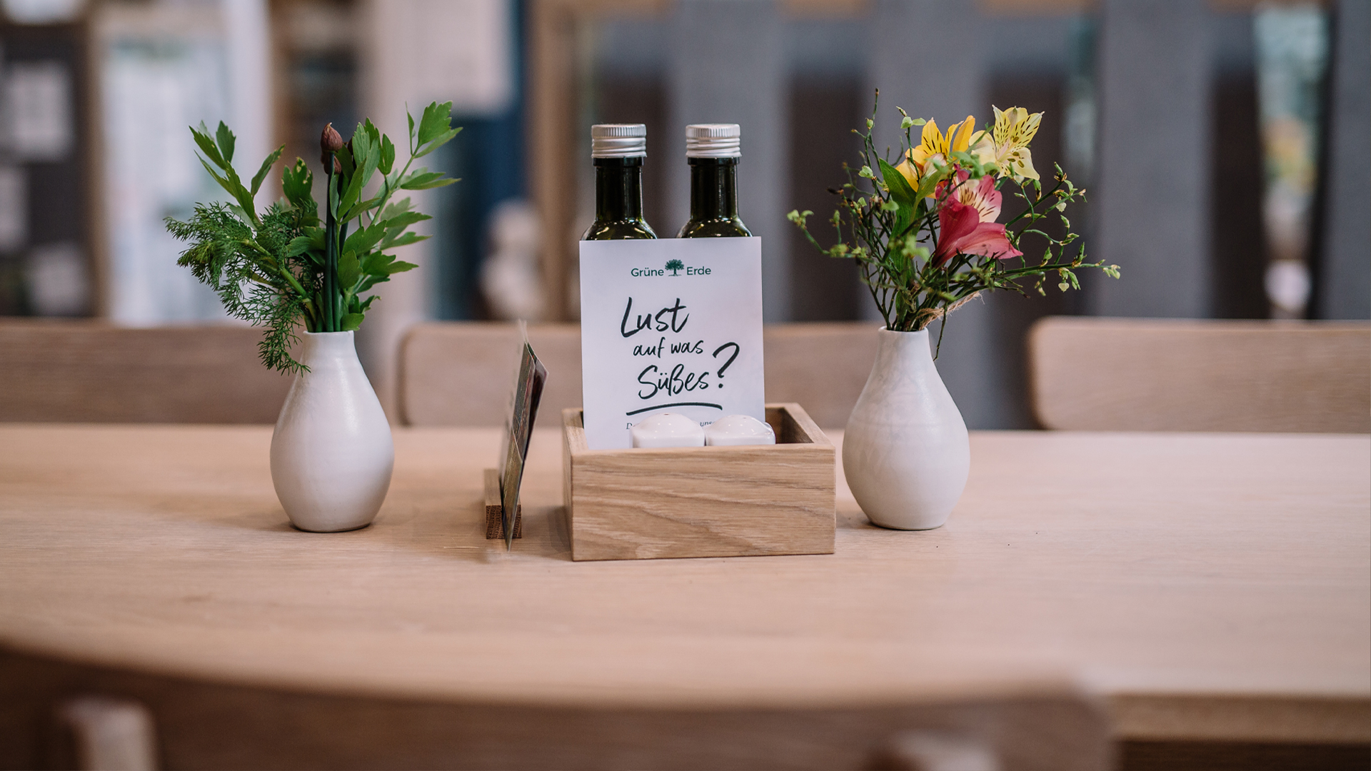 Holztisch mit kleinen Vasen Blumen und beschrifteter Karte in gemütlicher Umgebung