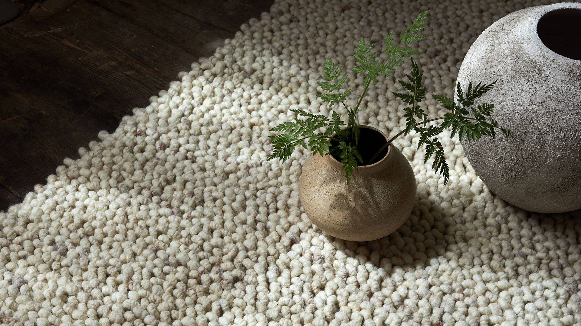Naturteppich mit Keramikvasen und einem dekorativen Zweig am Boden