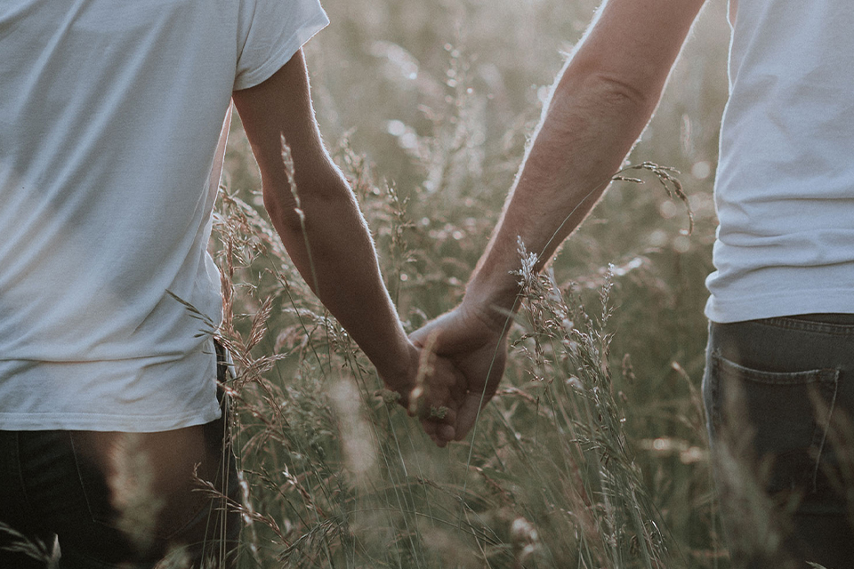 Ein paar hält sich an der Hand in einer hohen Wiese