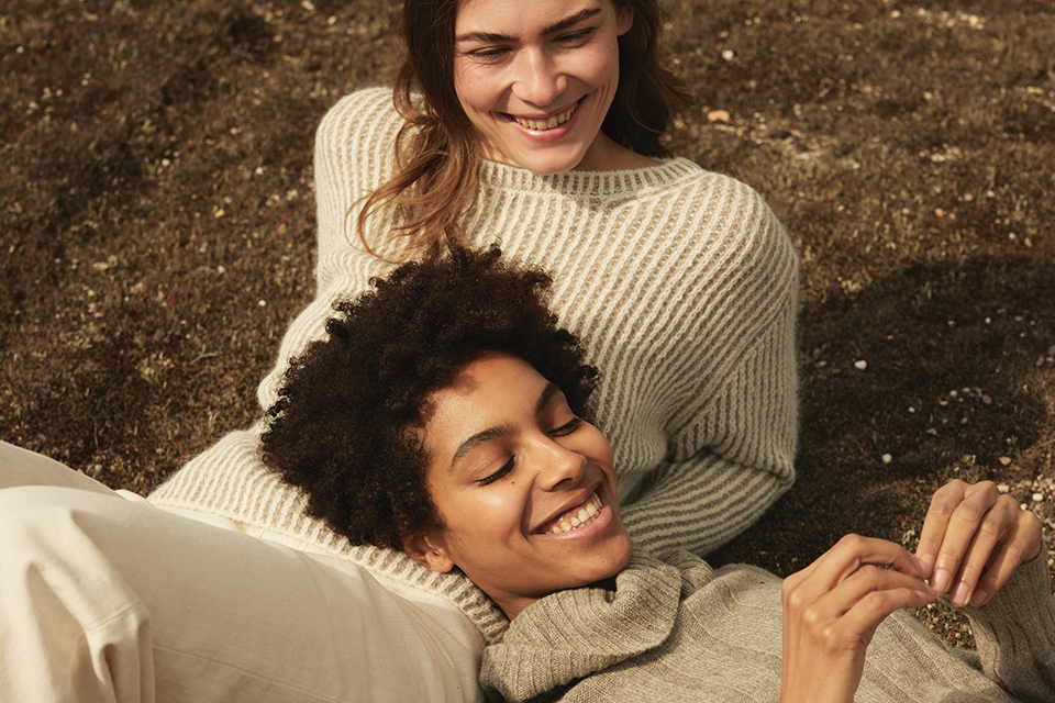 Zwei Frauen liegen gemeinsam lachend auf der Erde