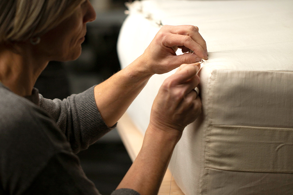 Frau näht sorgfältig eine Matratze zu