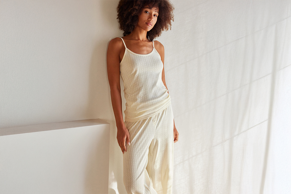 Frau in hellem Gewand steht vor neutralem Hintergrund